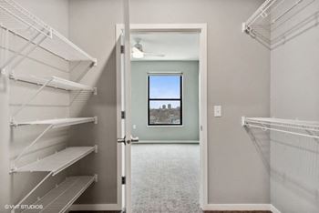 a walk in closet with a window and empty shelves